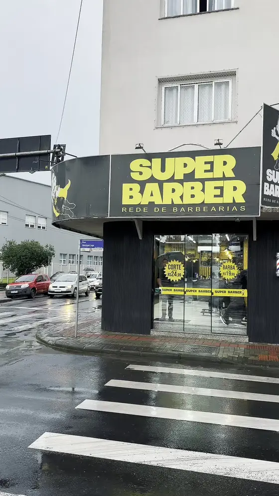 Fachada da Super Barber numa esquina, em dia de chuva